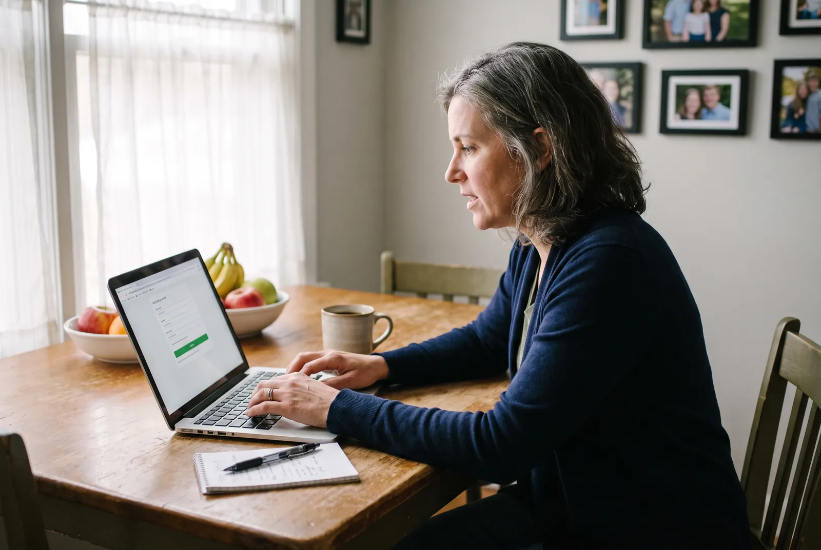 A woman at her kitchen table watching the live map of her mother's ride on a laptop