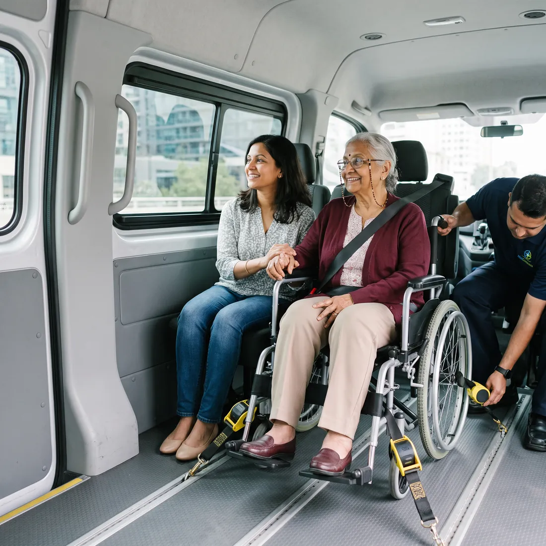 A rider secured in her wheelchair inside the van with four tie-down straps, her daughter seated beside her